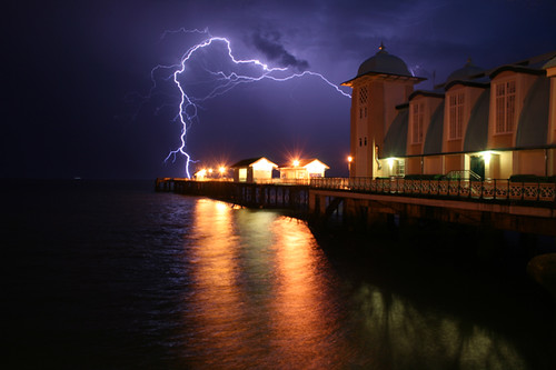 Penarth Pier takes a bolt of lightning. Lights reflecting on water and 