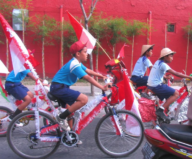 Schoolchildren riding bicycles in colours of Indonesian flag