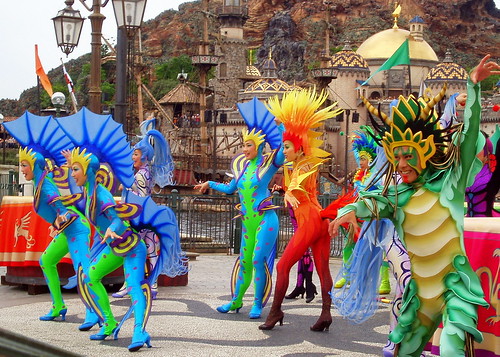 In select areas on shore, colorful dancers create a bright and high energy atmosphere as they swirl around with drums and staffs.
