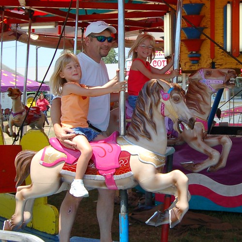 Dad and his girls enjoying the merry-go-round.