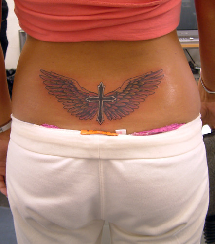 Lower back tattoo of a religions cross with wings.