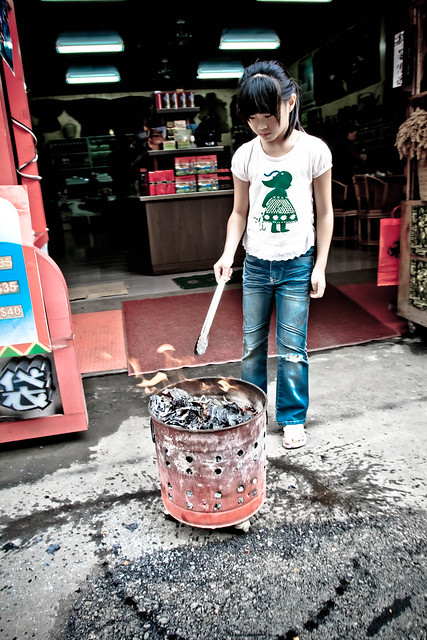 Girl tends a fire on WenHua St., near Sun Moon Lake, Taiwan