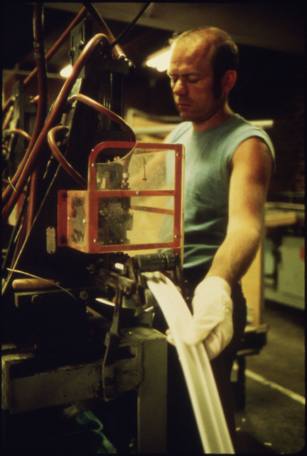 Employee of the BF Goodrich Co Working on a Machine That Makes Molding for Magnetic Door Seals for Various Brands of Refrigerators by The US National Archives
