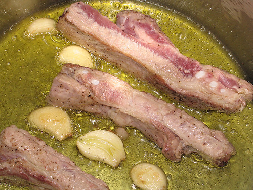 Pork spareribs frying in olive oil with garlic