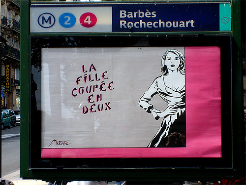 stencil graffiti from Miss.Tic: An image of a woman in a full-skirted, 50s style dress with princess neckline, one hand on her hip, to the right of the words, "la fille coupee en deux"  