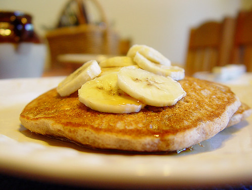 Cinnamon Vanilla Hazelnut Pancakes garnished with sliced banana and 100% pure maple syrup