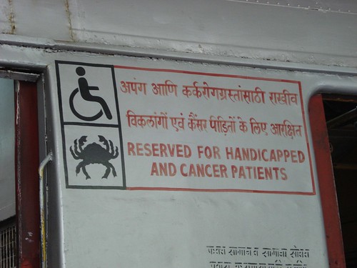 In India, a photo by Marc van der Chijs shows a train car door sporting a sign reading "Reserved for handicapped and cancer patients".  Next to the words are two icons for clarification: a person in a wheel chair, and a crab.