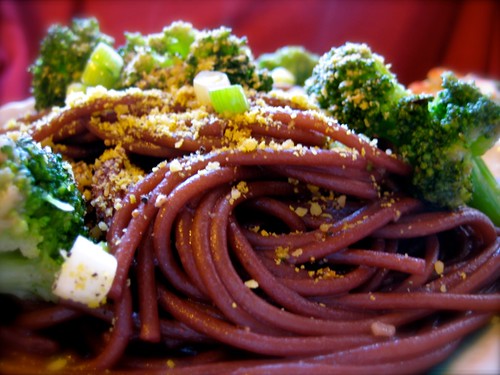 red wine spaghetti with salad in background