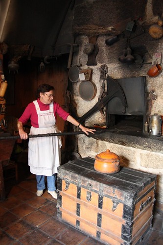 Doña Herminia de pie, con pala, frente al horno