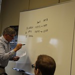A professor writes information on the white board for his class to copy down.