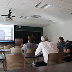 Students and professors watch a video together in a classroom.